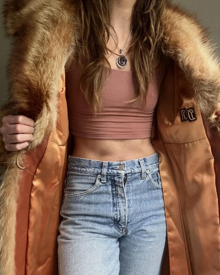 Anita opening a vintage fur-collared coat lined in copper satin, wearing a sterling silver amethyst pendant